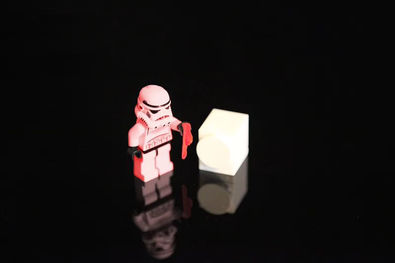 Kleine Lego-Szene mit einem Stormtrooper, einer roten Socke und einer weißen Waschmaschine vor schwarzem Hintergrund.
